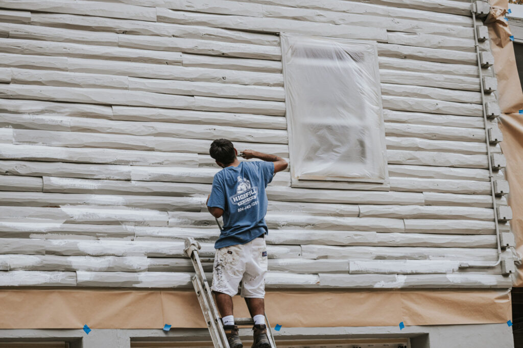 Worker painting exterior of Richmond home.